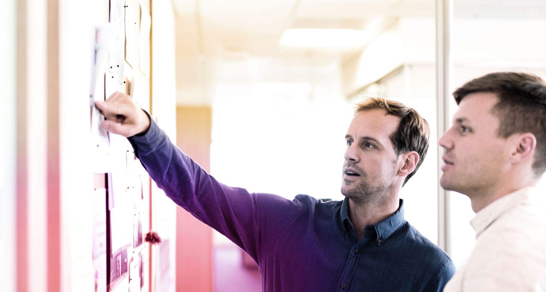 zwei Männer zeigen auf Wand